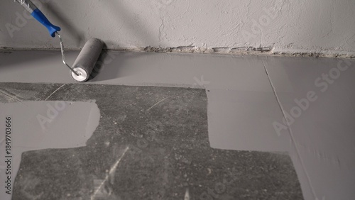 Foto Close-up view of a skilled worker applying a gray epoxy resin coating to a concr