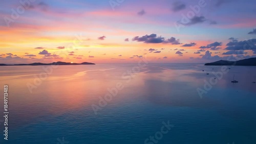A breathtaking aerial view of a tropical sunset with a colorful sky reflecting on the calm turquoise ocean and distant islands