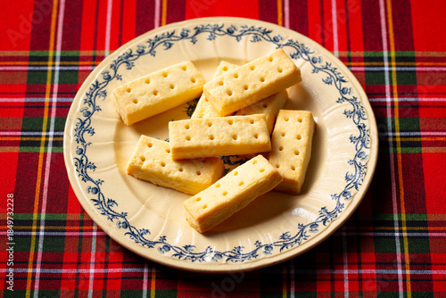 Foto Classic Scottish shortbread fingers on ornate plate, tartan backdrop, traditional tea time treat