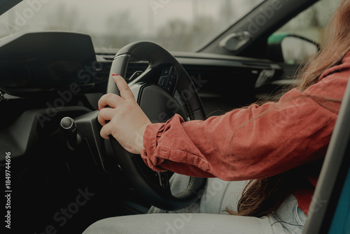 Female hands on steering wheel in modern car interior, calm driving concept