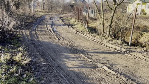 A dirt road is being worked on with heavy machinery showing tire tracks on the surface in a rural setting.