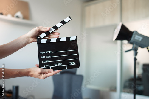 Person holding film clapperboard cueing start of production, motion video or picture, content creation