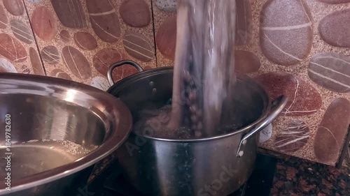 Adding raw octopus to a pot of boiling water in order to blanch it, seafood cooking preparation at home in a candid mundane moment of daily life