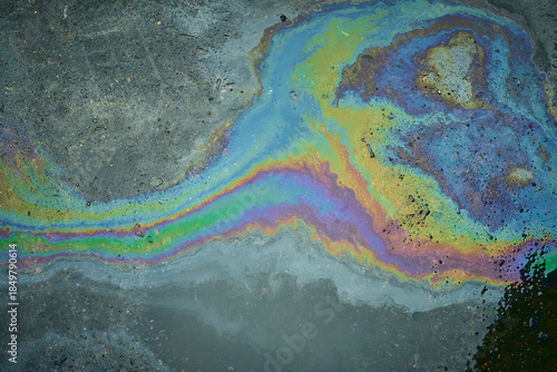 Photography Iridescent oil spill forming rainbow on wet asphalt