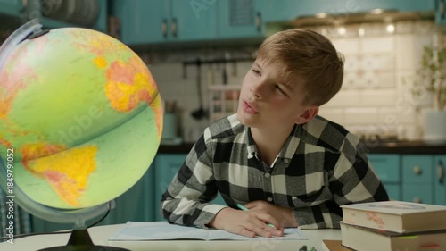 Boy Doing Homework Looking at Globe at Home
