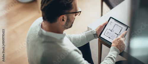 Man reviewing apartment floor plan on digital tablet  
