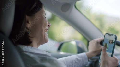 30s Woman Holding Cellphone while Video Chatting and Driving Car, unsafe distracted driving situation.