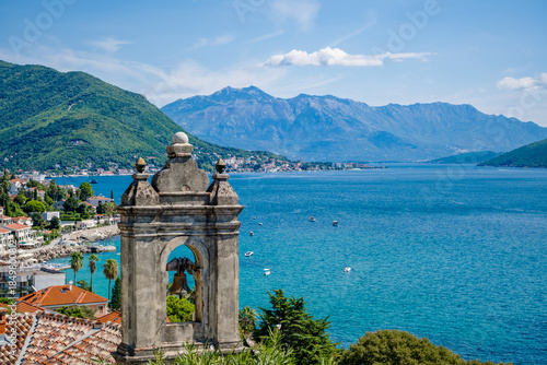 A scenic view of Herceg Novi, Montenegro, featuring a coastal landscape with mountains in the background and a historic stone structure in the foreground.
