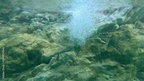Underwater dolly up to breaking the water surface, revealing a flowing natural spring among volcanic rocks that creates an otherworldly scene in JABA sulfur lagoon in Amlan, Negros Oriental, Philippin