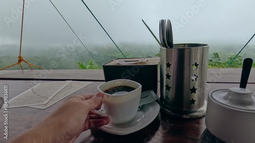 POV drinking black coffee at a balcony with the majestic view of forest covered by fog creating a warm and cozy aesthetic