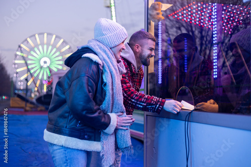 Couple buying tickets at amusement park on a winter night