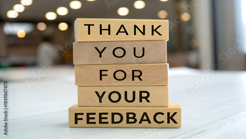 Wooden blocks stacked to spell out thank you for your feedback on a light surface in an office setting
