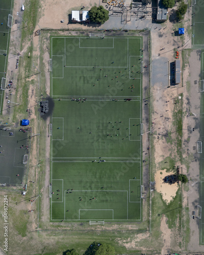 Cenital con dron de campo de fútbol dividido en tres canchas menosres para prácticas o fútbol infantil