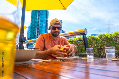 Canvastavla Tourist enjoying burger and beer at vancouver restaurant with city view