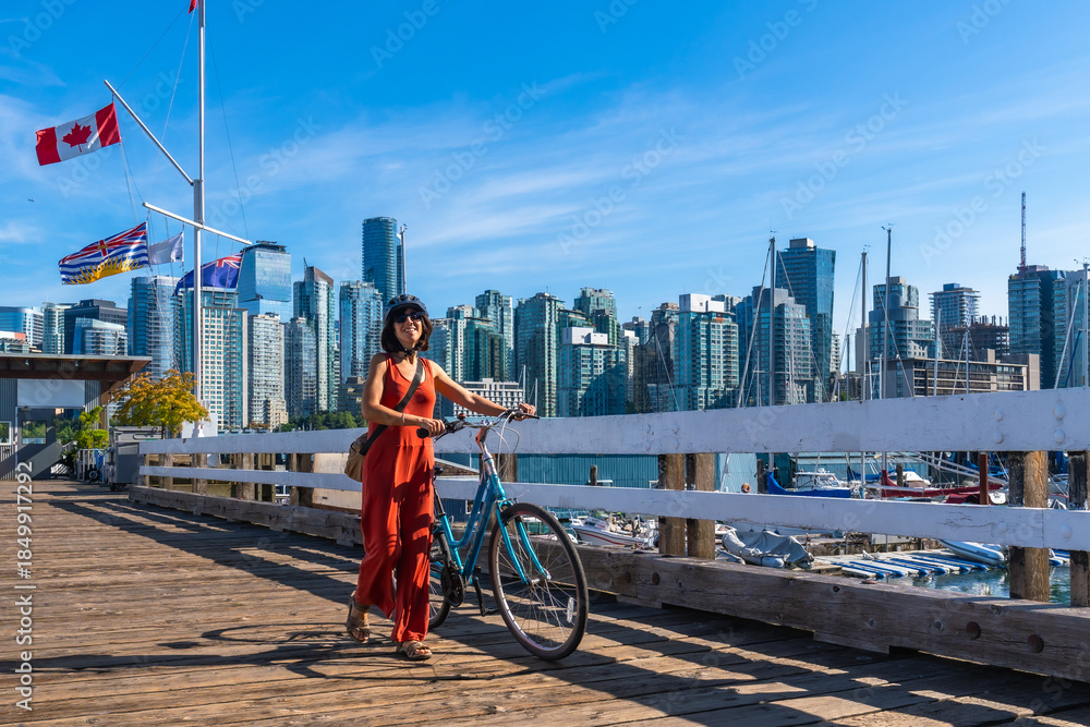 Obraz premium Tourist walking with bicycle on pier, enjoying vancouver skyline