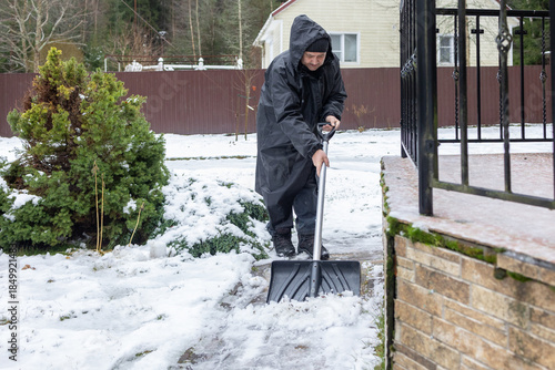 Elderly man shoveling snow in winter yard