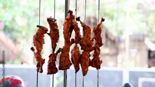 spicy tandoori chicken skewers hanging vertically at restaurant