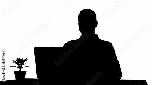 Silhouette of man working on laptop with potted plant on desk