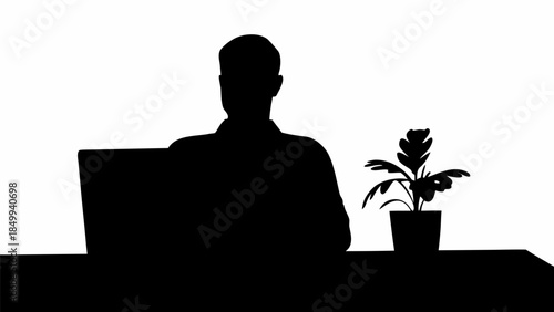 Silhouette of man working on laptop with potted plant on desk