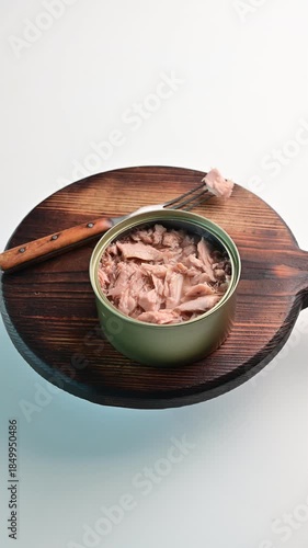 Tuna in a can on a wooden board with a fork ready for serving