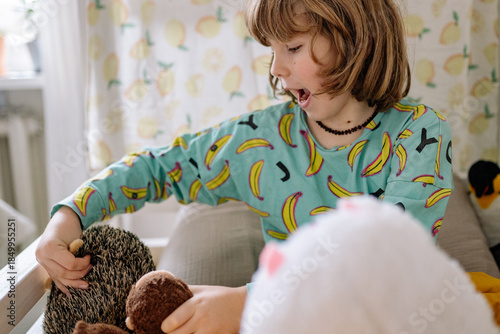 Child plays with stuffed animals in a cozy room during the afternoon