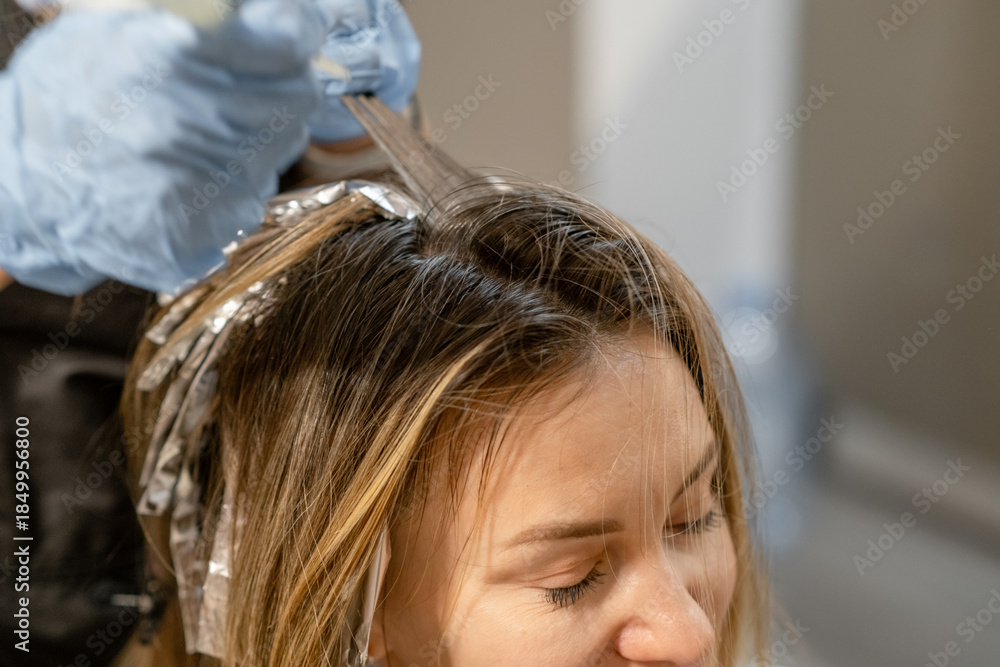 Fototapeta premium Hair coloring process taking place in a salon with foils applied to a womans head during a beauty treatment