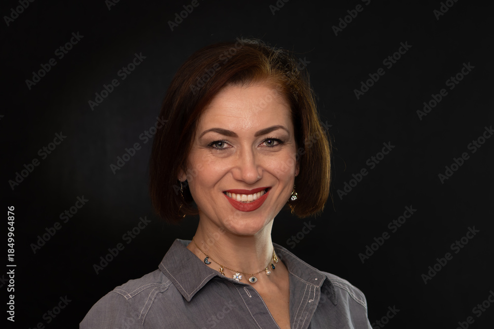 Fototapeta premium Portrait of a mature woman with an open gaze against a dark background.