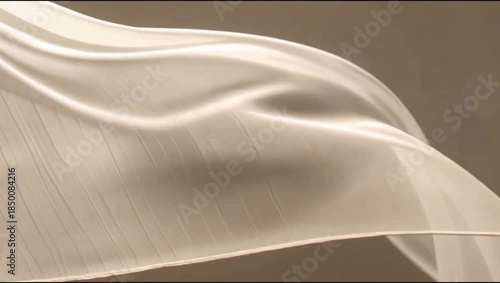 A flowing, elegant light beige fabric with subtle texture, creating soft drapes and shadows against a warm background.