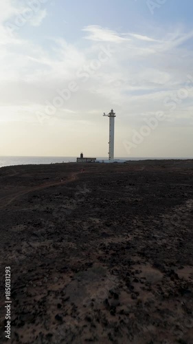 Vertical Low Altitude Drone Pan Over Arid Volcanic Land Towards Faro de Pechiguera Lighthouse and Atlantic Ocean in Lanzarote, Canary Islands.