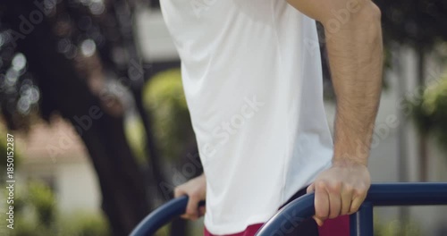 
 Athlete performs dips exercise outdoors, street workout, middle close-up, slow motion