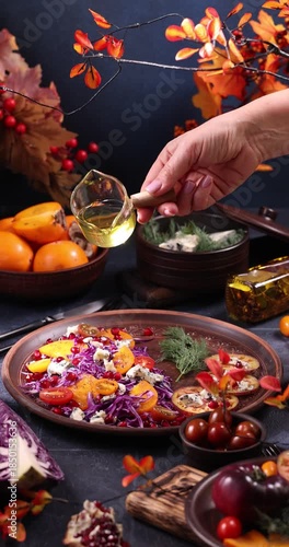 Hand pouring oil on a delicious autumn salad