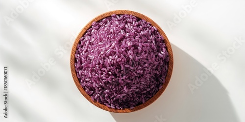 Wooden bowl filled with purple glutinous rice grains on a white background serving as a kitchen display, Thai rice, Top view