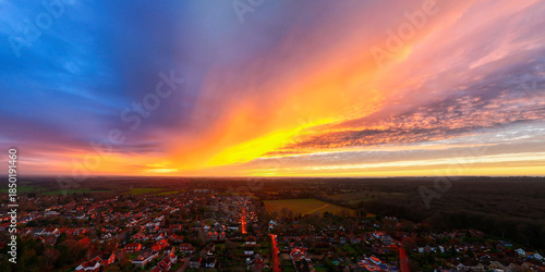 Aerial view of a sunset blazing with fiery oranges and yellows over the town, contrasting with the cool blues of the sky, Henley-on-Thames, Oxfordshire, England.