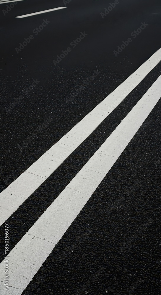 Fototapeta premium Diagonal perspective of thick parallel white lines painted on black street asphalt, symbolizing road safety and movement in an urban area, safety, graphic, road