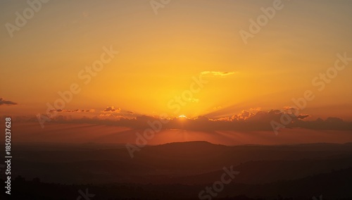 Wide-angle scene of sunrise with vibrant orange hues and scattered clouds, capturing the transition from night to day
