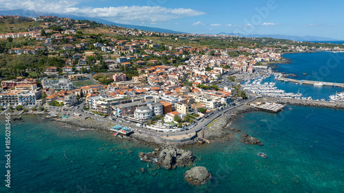 Wallpaper Mural Aerial view of the town of Aci Trezza overlooking the Mediterranean Sea, in the province of Catania, Sicily, Italy. In the background is the marina of the city. It's a sunny summer morning. Torontodigital.ca