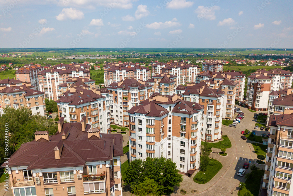 Fototapeta premium Top view of urban developing city landscape with tall apartment buildings and suburb houses. Drone aerial photography.