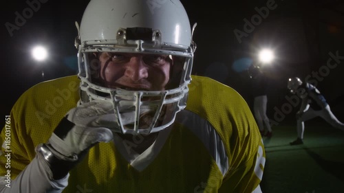 Medium portrait of strong, fearless Caucasian male American football player in protective gear putting on mouthguard, roaring and beating on helmet to intimidate rival team opponents