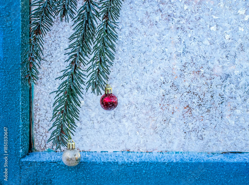 estive background with a spruce branch with balls hanging on a window glass c...