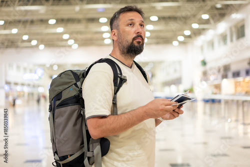 Traveler in airport on his phone checking the directions for his flight. High quality photo
