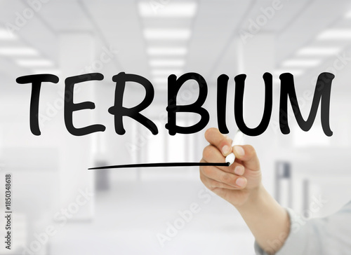 Wallpaper Mural A conceptual image showing the word terbium handwritten in bold black letters on transparent glass, with a blurred modern white office interior in the background, symbolizing this rare earth element’s Torontodigital.ca