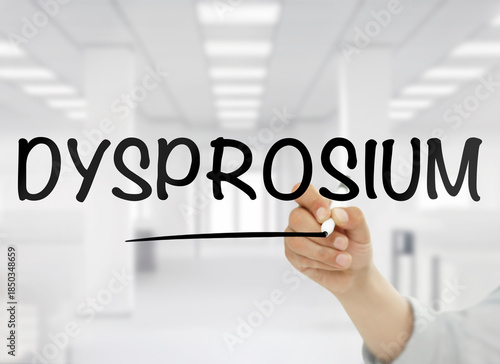 Wallpaper Mural A conceptual image showing the word dysprosium handwritten in bold black letters on transparent glass, with a blurred modern white office interior in the background. This rare earth element theme is s Torontodigital.ca