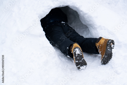 Person Partially Buried in Snow Cave - Only Legs Visible. High quality photo