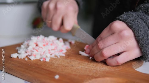 Hands Dicing Imitation Crab Sticks on Wooden Cutting Board for Salad Preparation
