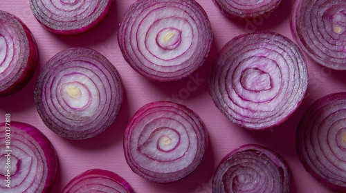 Overhead shot of halved red onions arranged on a pink surface, revealing concentric rings and fleshy texture