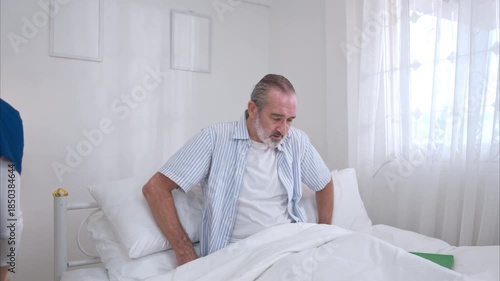 A female nurse assists an elderly patient in bed with food and medication before meals