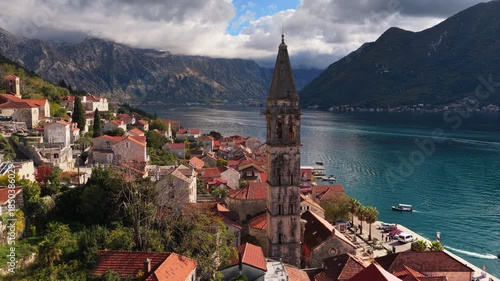 Wallpaper Mural Aerial drone view of the bell tower in Perast rising above traditional stone houses, with the Bay of Kotor and steep mountains visible behind it. Bay of Kotor, Montenegro Torontodigital.ca