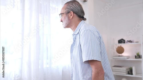 Senior man with a walking aid looking out the window, concept of elderly life and rehabilitation