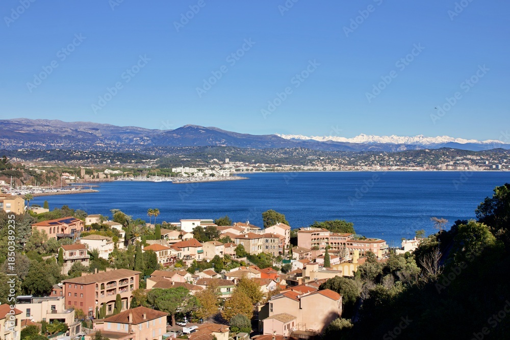 Obraz premium Stunning panoramic winter landscapes of the French Riviera, featuring the coastal towns of Cannes and Théoule-sur-Mer. The Mediterranean Sea contrasts beautifully with the snow-covered mountains
