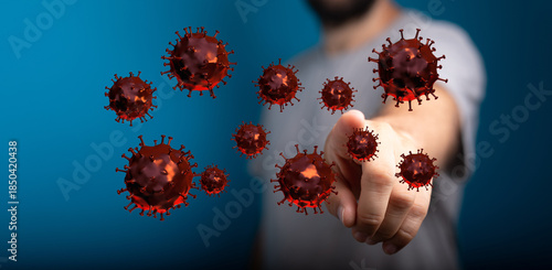 Conceptual image of a man pointing at airborne Coronavirus cells, illustrating the spread of infection, highli